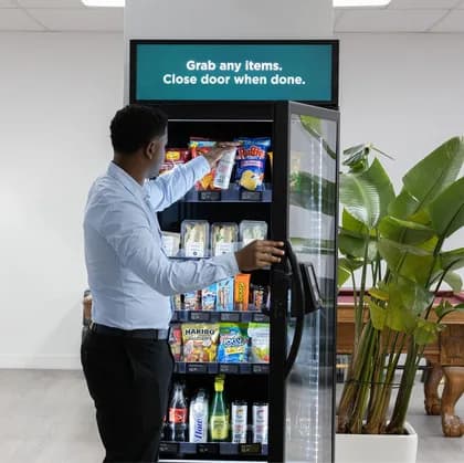 Professional grabbing a drink from a smart cooler in an office lounge